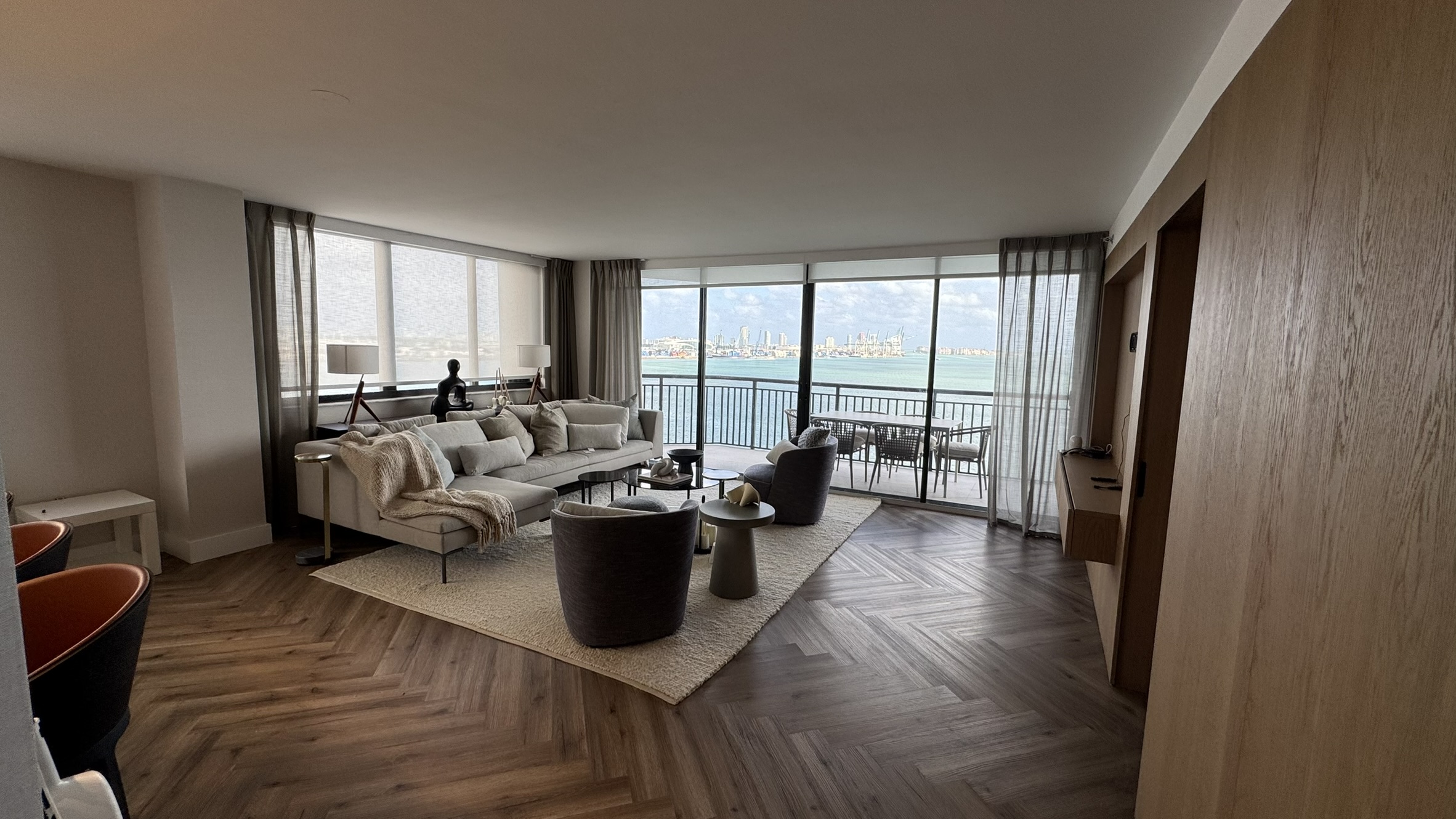 Herringbone flooring, a wood-paneled wall and a seating area facing the balcony and water view.