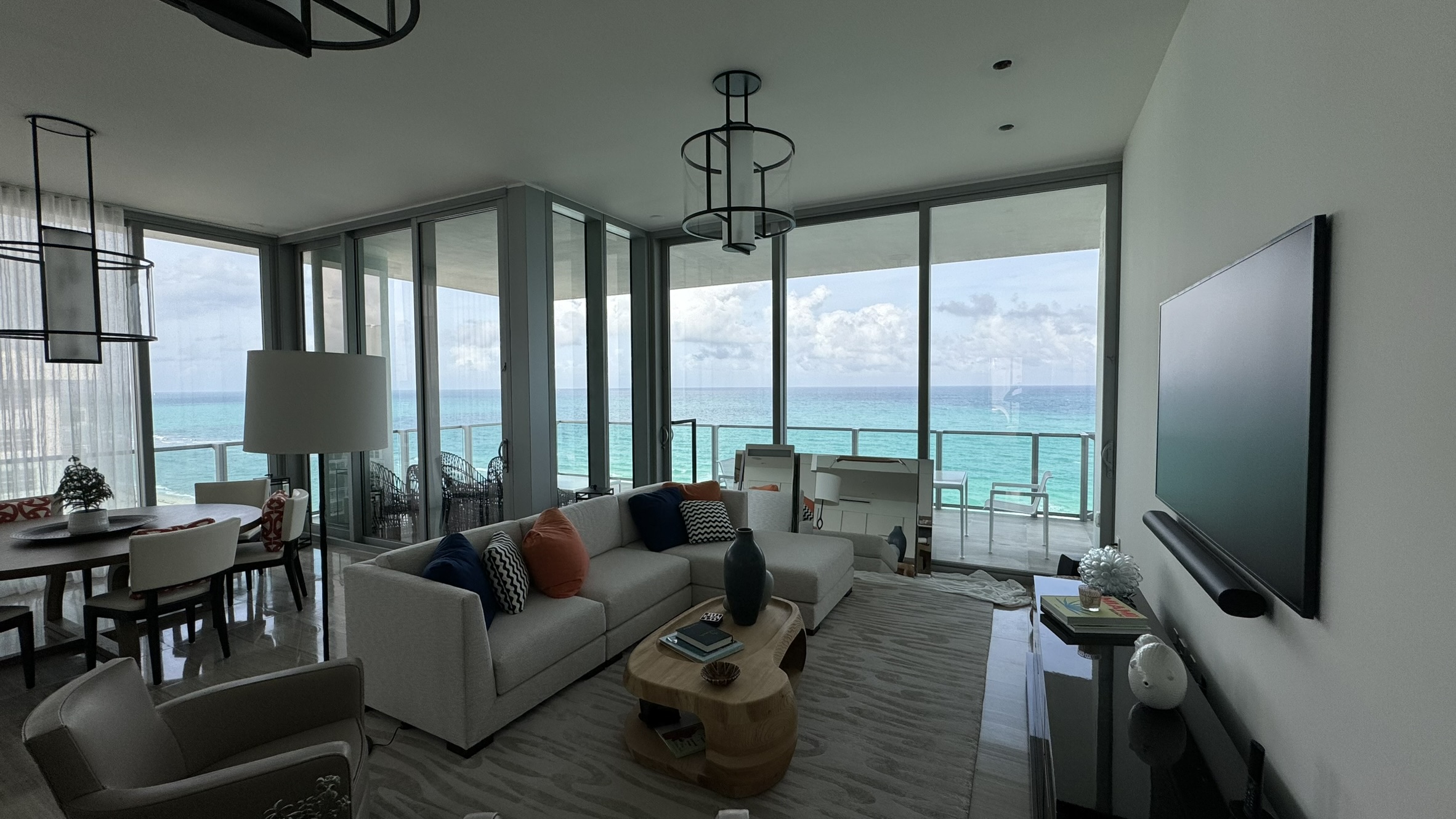 A bright living area with corner glazing, a neutral sofa and an open view toward the ocean.